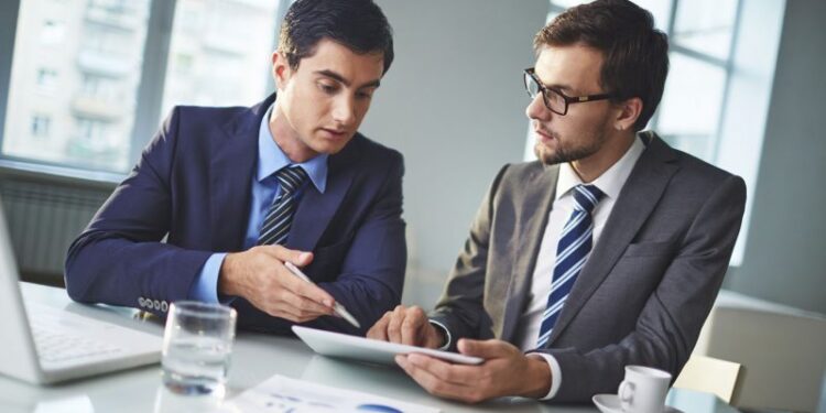 Male colleagues discussing new project or data in office