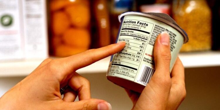 Person Reading Nutrition Label on Packaged Food