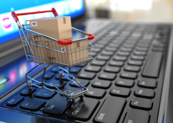 E-commerce. Shopping cart with cardboard boxes on laptop. 3d