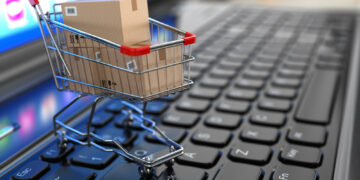 E-commerce. Shopping cart with cardboard boxes on laptop. 3d