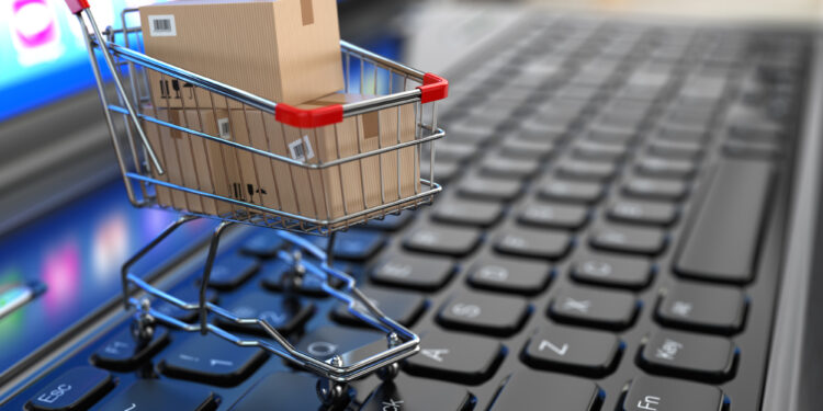 E-commerce. Shopping cart with cardboard boxes on laptop. 3d
