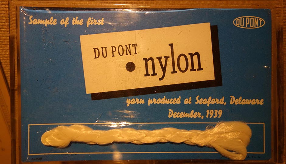 Etiqueta con una muestra de la primera hebra de nailon fabricada por DuPont en Seaford, Delaware, en diciembre de 1939. La pieza conserva el logotipo histórico de la compañía y forma parte de los archivos conmemorativos de la empresa.